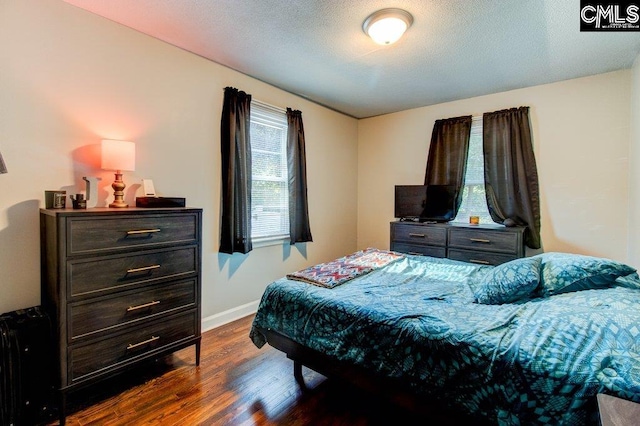 bedroom with a textured ceiling and dark wood-type flooring