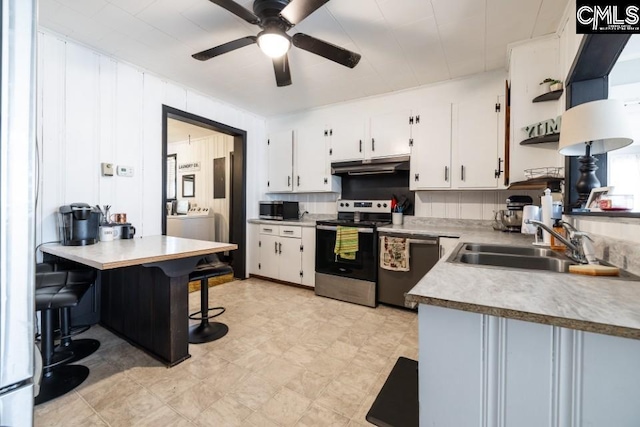 kitchen with backsplash, white cabinets, ceiling fan, a kitchen bar, and stainless steel appliances