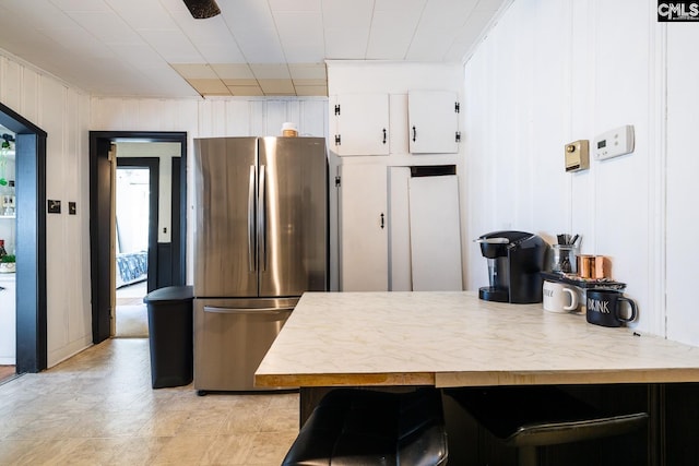 kitchen featuring white cabinets, a kitchen breakfast bar, kitchen peninsula, and stainless steel refrigerator