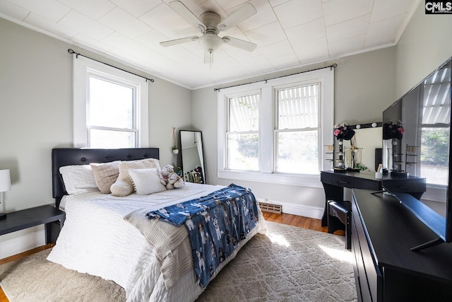 bedroom with hardwood / wood-style flooring, multiple windows, ornamental molding, and ceiling fan