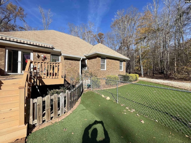 view of side of property with a wooden deck and a lawn