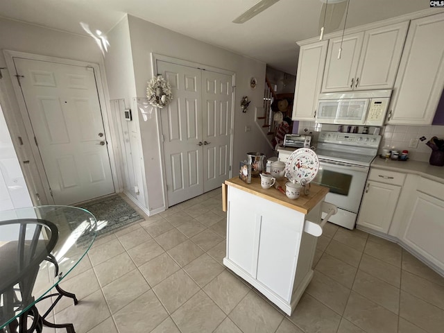 kitchen with tasteful backsplash, white cabinetry, light tile patterned flooring, and white appliances