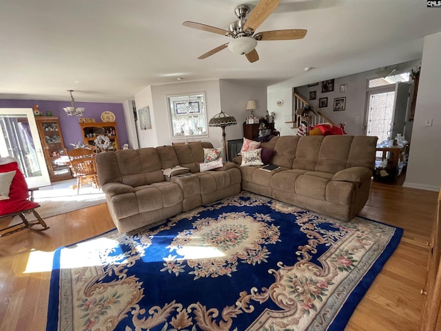 living room featuring wood-type flooring and ceiling fan with notable chandelier