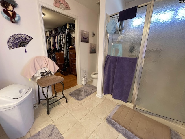 bathroom with tile patterned floors, a shower with door, and toilet