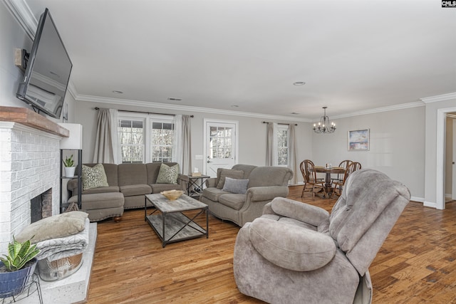 living room with a fireplace, hardwood / wood-style floors, a notable chandelier, and ornamental molding