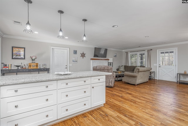 kitchen featuring pendant lighting, white cabinets, light stone countertops, ornamental molding, and light hardwood / wood-style floors