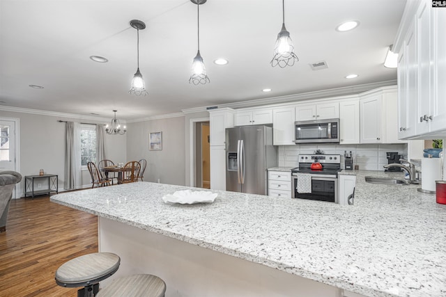 kitchen featuring sink, white cabinets, decorative light fixtures, and appliances with stainless steel finishes