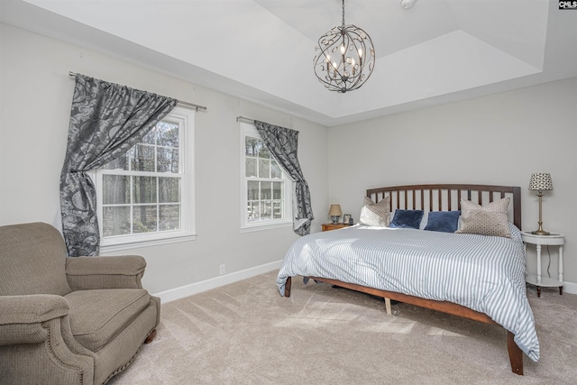 carpeted bedroom with a raised ceiling and an inviting chandelier