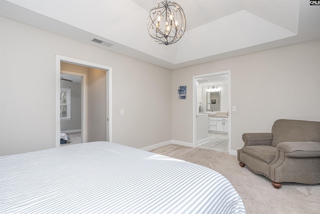 carpeted bedroom featuring a chandelier and ensuite bath