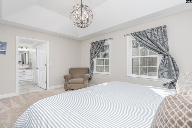 carpeted bedroom with connected bathroom, a raised ceiling, and a notable chandelier