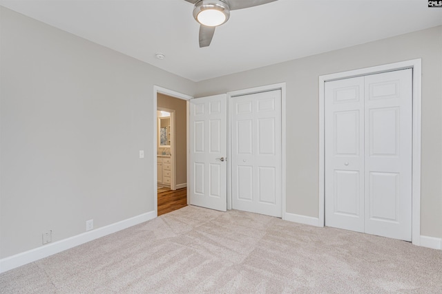 unfurnished bedroom featuring light carpet, two closets, and ceiling fan