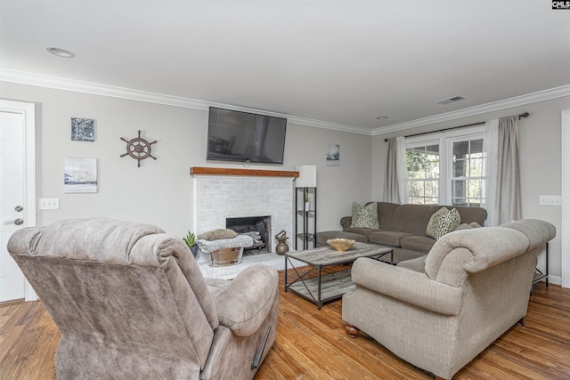 living room featuring a fireplace, light wood-type flooring, and crown molding