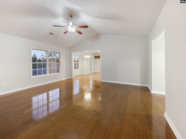 spare room featuring ceiling fan with notable chandelier, wood-type flooring, and lofted ceiling