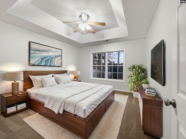 bedroom featuring carpet floors, a tray ceiling, and ceiling fan