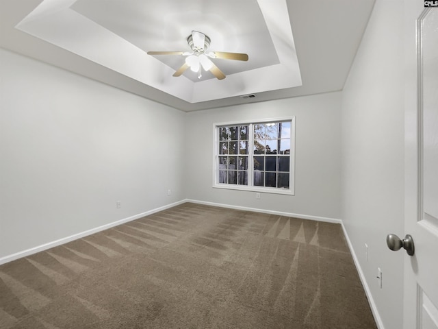 carpeted empty room with a raised ceiling and ceiling fan