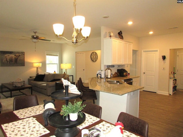 dining area with sink, hardwood / wood-style floors, and ceiling fan with notable chandelier