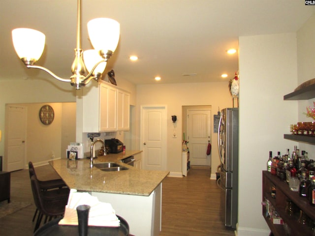 kitchen featuring kitchen peninsula, sink, stainless steel fridge, decorative light fixtures, and white cabinetry