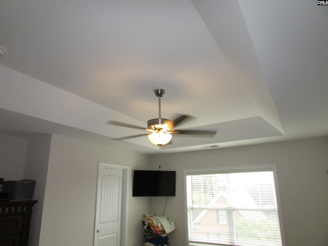 interior details with ceiling fan and a raised ceiling