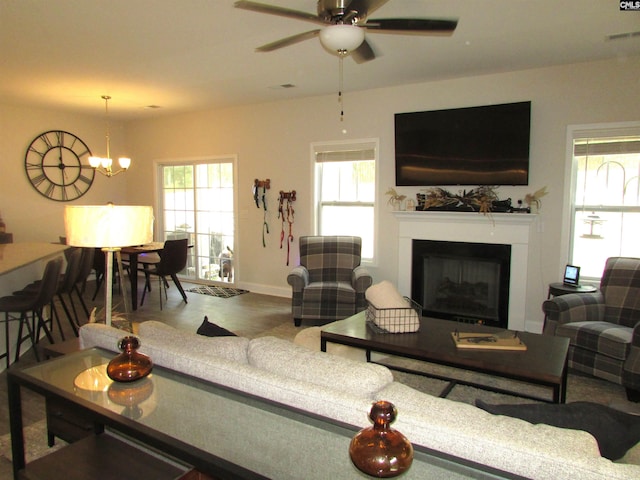 living room featuring ceiling fan with notable chandelier and plenty of natural light