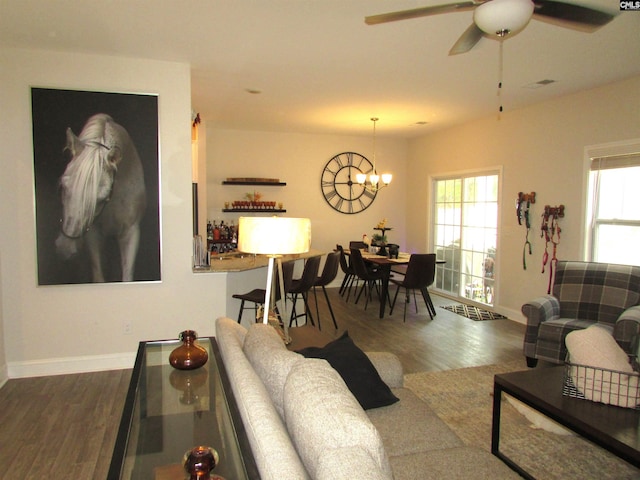 living room with ceiling fan with notable chandelier and dark hardwood / wood-style floors