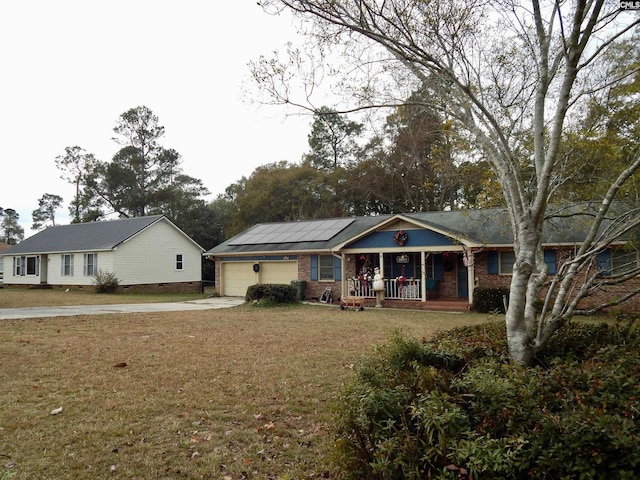 view of front of house with a front yard, covered porch, a garage, and solar panels