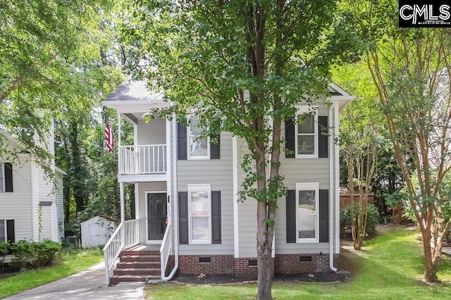 view of front of property featuring a shed, a balcony, and a front yard