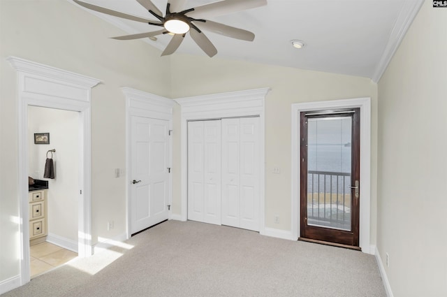 unfurnished bedroom featuring ceiling fan, light colored carpet, vaulted ceiling, access to outside, and a closet