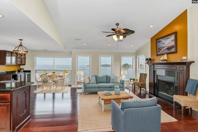 living room with crown molding, ceiling fan with notable chandelier, dark wood-type flooring, and vaulted ceiling