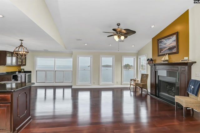 living room featuring ceiling fan with notable chandelier, crown molding, dark wood-type flooring, and vaulted ceiling