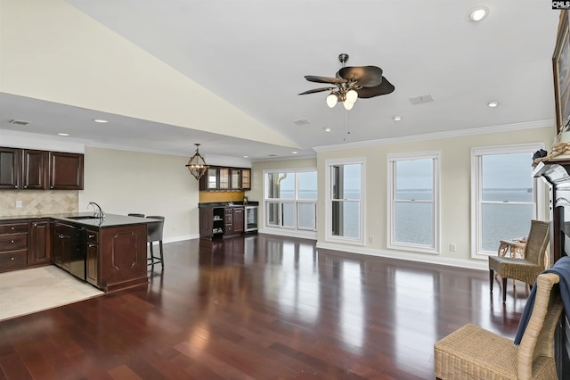 kitchen featuring decorative backsplash, crown molding, sink, wood-type flooring, and a breakfast bar area