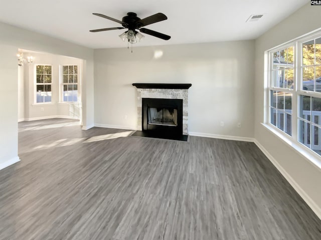 unfurnished living room featuring a fireplace, dark hardwood / wood-style flooring, and ceiling fan with notable chandelier