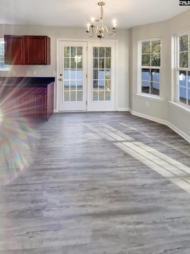 unfurnished dining area with wood-type flooring and an inviting chandelier