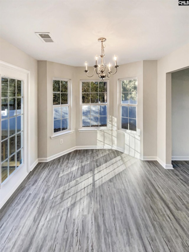 unfurnished dining area featuring hardwood / wood-style floors and a notable chandelier