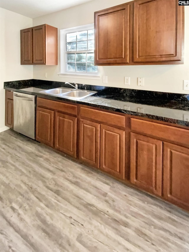 kitchen with dishwasher, light hardwood / wood-style floors, dark stone counters, and sink