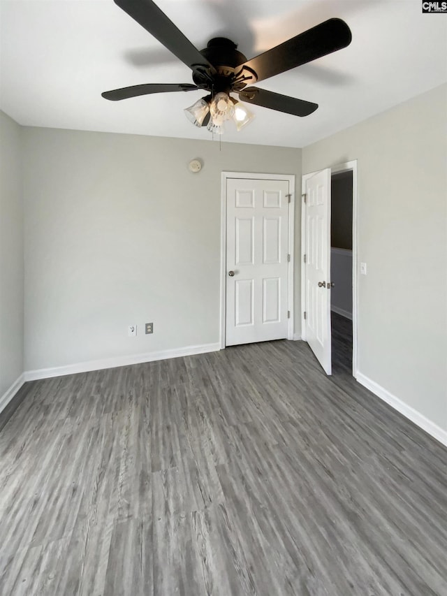 unfurnished bedroom with ceiling fan and dark wood-type flooring