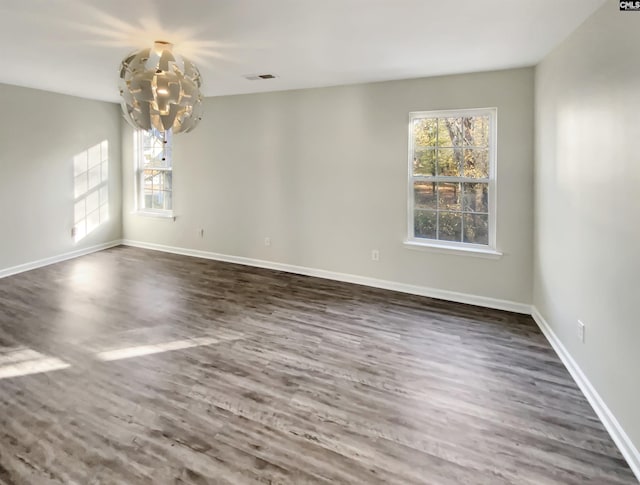 unfurnished room featuring a chandelier and dark wood-type flooring