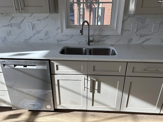 kitchen featuring gray cabinets, stainless steel dishwasher, tasteful backsplash, and sink