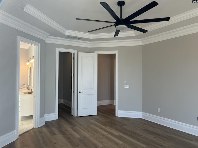 unfurnished bedroom featuring a walk in closet, dark hardwood / wood-style flooring, ensuite bathroom, ornamental molding, and ceiling fan