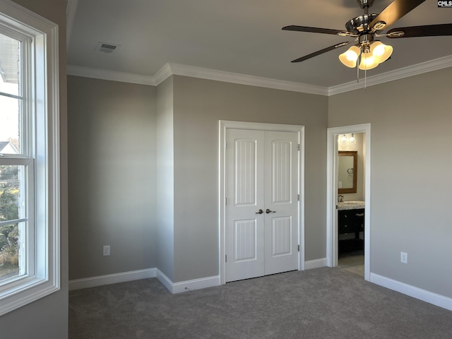 unfurnished bedroom with dark colored carpet, connected bathroom, ceiling fan, and ornamental molding