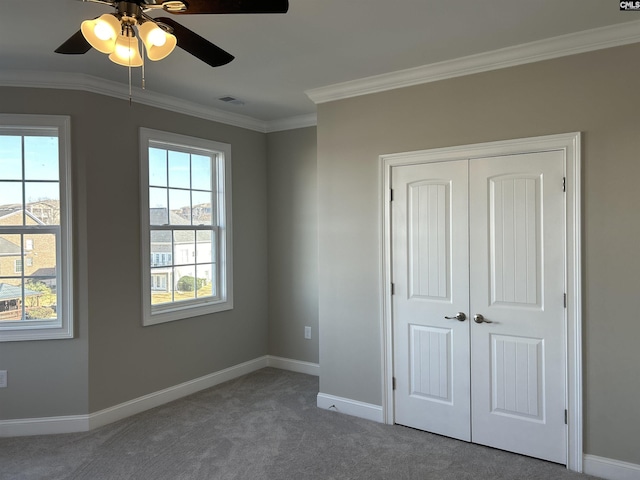 unfurnished bedroom with carpet, ceiling fan, crown molding, and a closet