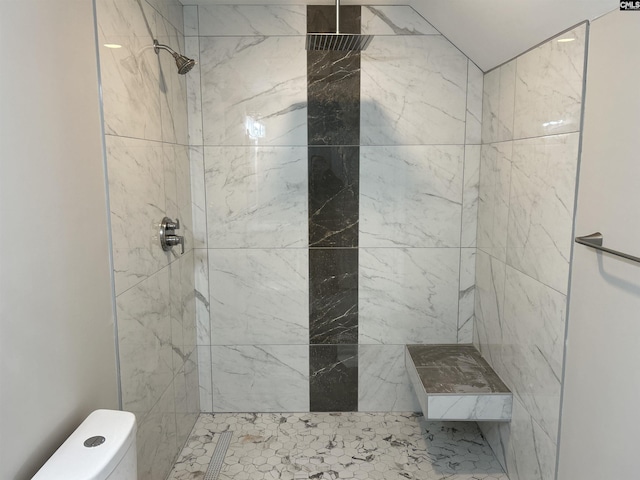 bathroom featuring a tile shower and toilet