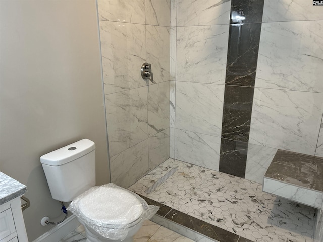 bathroom with toilet, a tile shower, and vanity