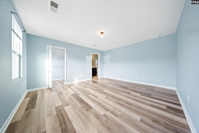 unfurnished bedroom featuring a closet, light hardwood / wood-style flooring, and a spacious closet