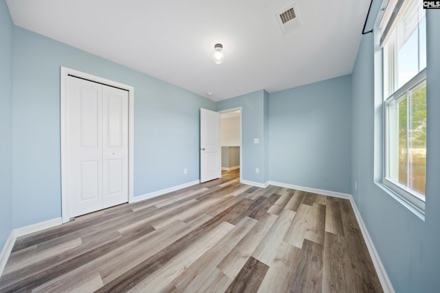 unfurnished bedroom with light hardwood / wood-style flooring and a closet