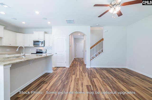 kitchen featuring decorative backsplash, light stone counters, stainless steel appliances, dark hardwood / wood-style floors, and white cabinetry