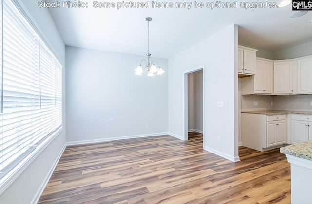 kitchen with backsplash, white cabinetry, hardwood / wood-style floors, and a chandelier