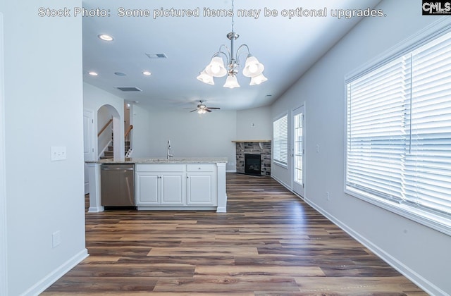 kitchen featuring pendant lighting, dishwasher, ceiling fan with notable chandelier, a fireplace, and dark hardwood / wood-style flooring