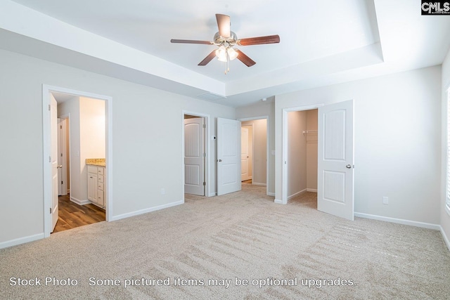 unfurnished bedroom with light carpet, a walk in closet, ensuite bath, ceiling fan, and a closet