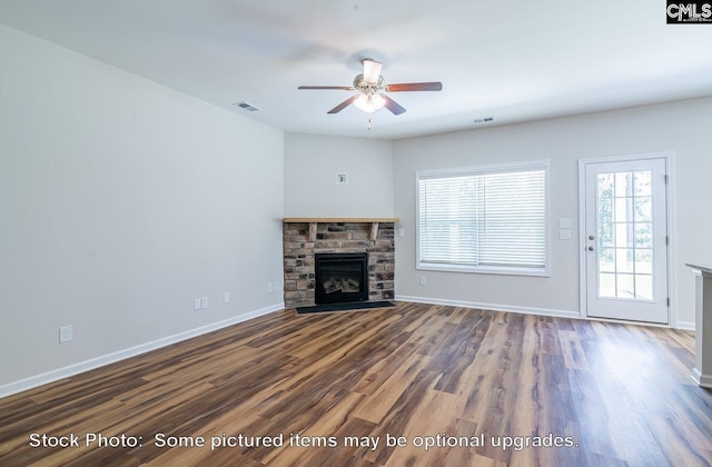 unfurnished living room featuring a stone fireplace, ceiling fan, and dark wood-type flooring