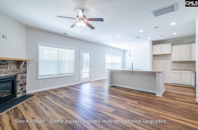 unfurnished living room featuring sink, ceiling fan, dark hardwood / wood-style flooring, and a fireplace